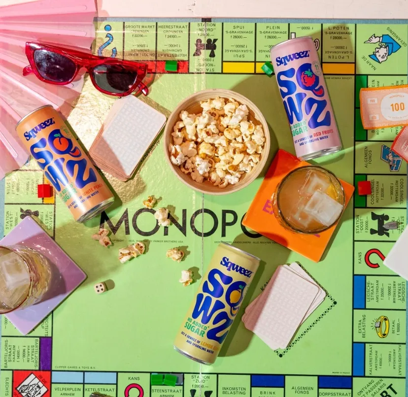 bebidas saludables sqweez y objetos coloridos sobre tablerlo monopoly